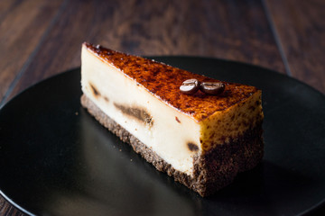 Coffee Cheesecake on Black Plate with Dark Wooden Surface.