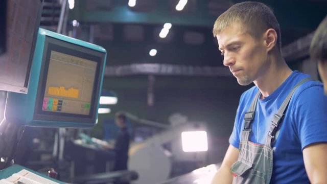 Engineer working with computer touchscreen, checking a ready-mady newspaper.
