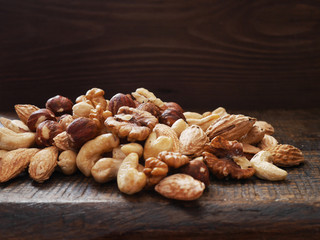 Different nuts (walnut, cashew, hazelnut, almonds)  on a wooden board. 