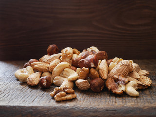 Different nuts (walnut, cashew, hazelnut, almonds)  on a wooden board. 