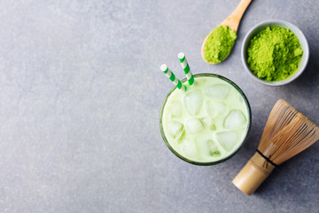 Matcha, green tea ice tea in glass. Grey stone background. Top view. Copy space.