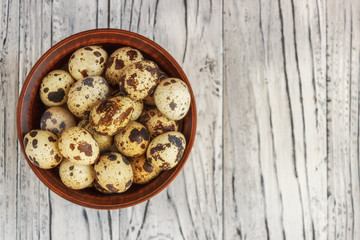 Quail eggs in a clay plate on a wooden background, a plate for storing quail eggs, a symbol of the Easter season. Healthy eating.