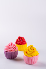 Three miniature multicolored sugar cupcakes on light background