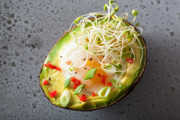 egg baked in avocado with spring onion and alfalfa sprouts