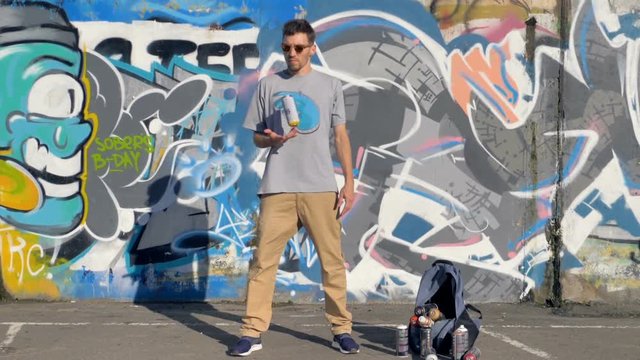 Young artist is juggling a spray paint in his right hand.