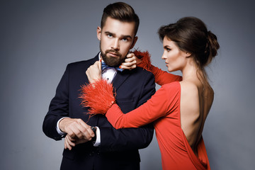 Woman in beautiful red dress and man wearing blue classical suit with bow tie.