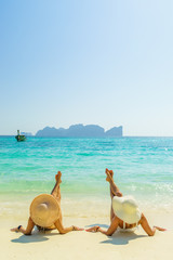 Fototapeta na wymiar Two 2 young beautiful girls sunbathing on the tropical beach