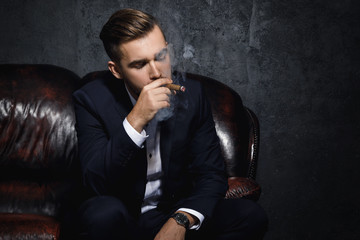 Handsome rich man is smoking cigar