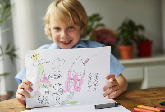 Child holding a drawing of a house and family