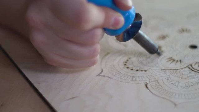 A woman burns on a tree with a pyrograph