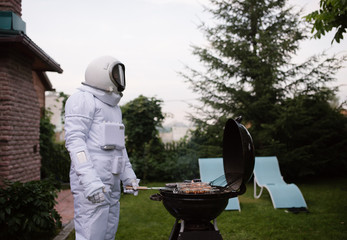 Man in space suit grilling meat