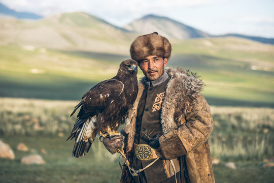 portrait of a proud kyrgyz eagle hunter with his golden eagle on his arm