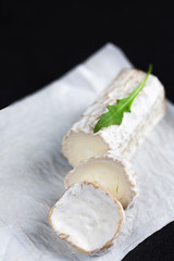 Stick of a goat cheese on black stone background. Fresh goat cheese with copy space