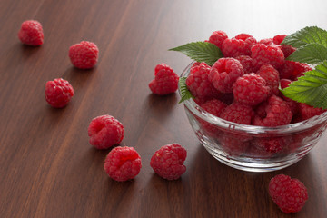 Red raspberries in a bowl on wooden background
