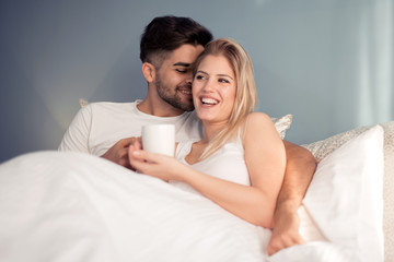 Picture of young couple drinking coffee in bed.