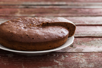chocolate sponge cake on old wooden background.