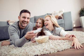 Family lying on the floor watching TV together.