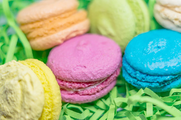 french tender dessert macaroons of different colors on green cut strips paper