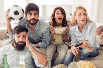 Cheerful group of friends watching football game on tv