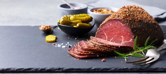 Roasted beef, pastrami on slate cutting board. Copy space