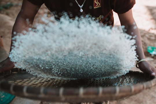 Crop woman winnowing rice