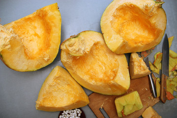 Cubes of a carved ripe pumpkin with a cutting board and a knife on the table. The concept of vegetarian food. View from above.