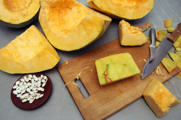 Cubes of a carved ripe pumpkin with a cutting board and a knife on the table. The concept of vegetarian food. View from above.