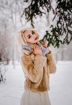 A stunning girl standing by the trees in a snowy forest