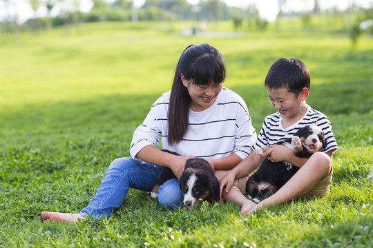 little asian boy holding his puppy sitting with his mother on th