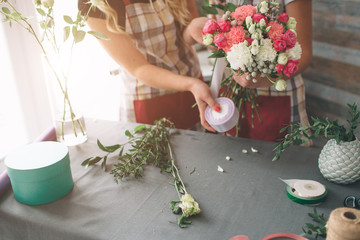 Flowers delivery top view. Florists creating order, making rose bouquet in flower shop. Two female florists are doing bouquets. One woman collecting roses for a bunch, another girl is working too.