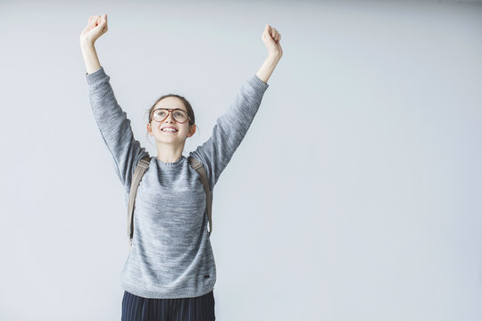 Happy young female student raised arm up  and looking up