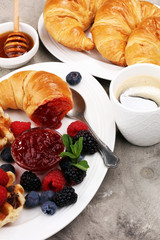 Delicious breakfast with fresh croissants and ripe berries and jam