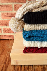 Knitted scarves of different colours and a hat are piled carefully