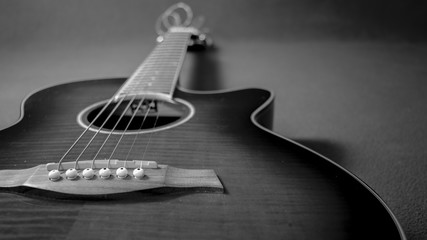 Retrato de una hermosa guitarra electroacústica situada a la izquierda de la imagen, mostrando el puente, la boca, el cuello y sus cuerdas