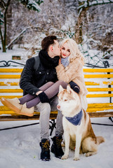 Sweet couple hug each other on a bench with her dog