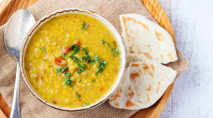 Lentil soup with pita bread in a ceramic white bowl on a wooden background. Top view. Copy space.