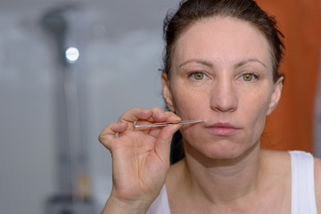 Woman plucking long hairs on her upper lip