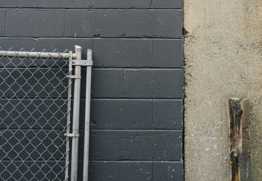 Chain-link fence leaning against building wall