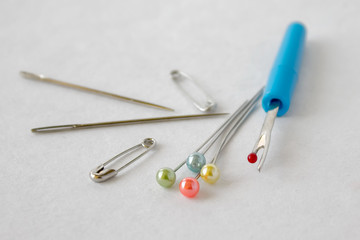 Sewing utensils needles, pins on white background.