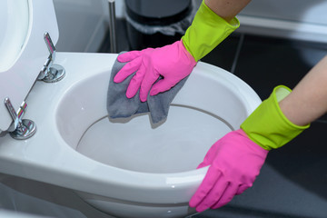Person wearing gloves wiping out a toilet