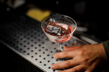Red cocktail with ice on the bar