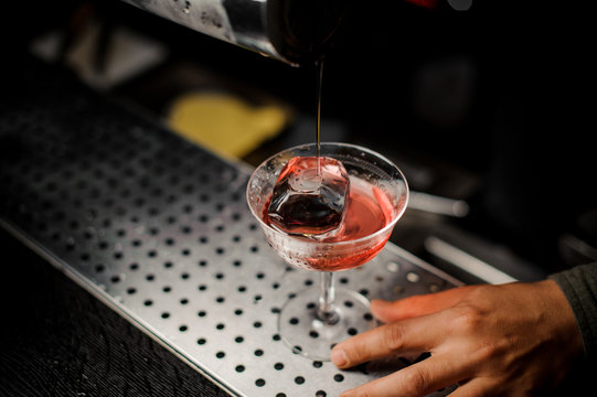 Red cocktail with ice on the bar counter