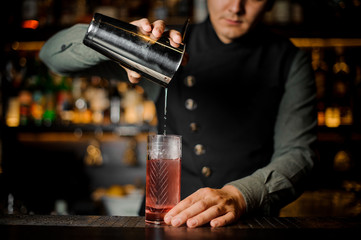 Bartender is making fresh light red cocktail