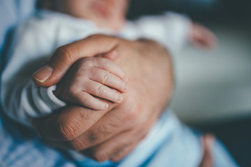 small hand of a newborn supported by the big hand of his father