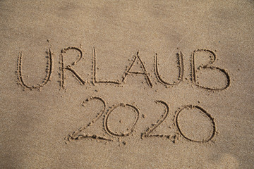 Das Wort URLAUB 2020 in den Sand geschrieben