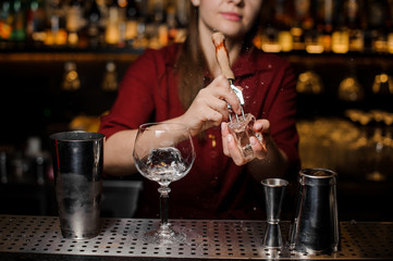 Bartender girl breaking a piece ice for the cocktail