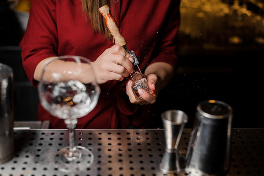 Bartender girl breaking ice for the cocktail