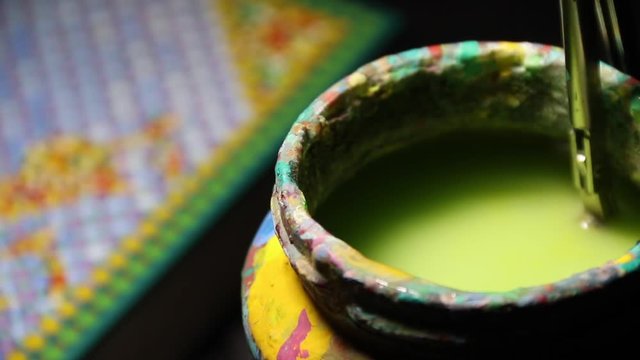 Close Up of the jar with colored water for brush and hand cleaning brush in water