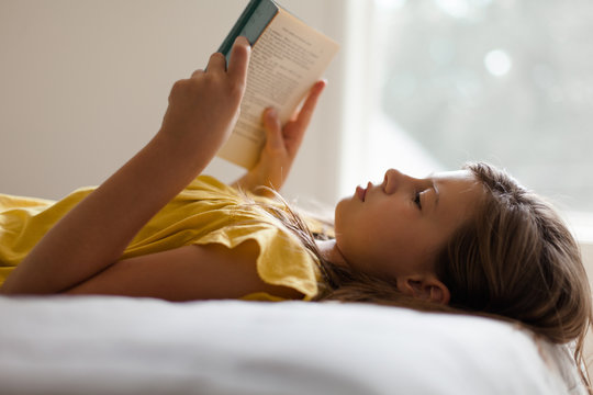 Girl reading a book at home by window