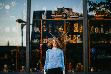 Young odd unusual girl playing with her beautiful hair in front of shop showcase. Fabulous teenager with passionate sensual face portrait. Blue eyed babe fashion portrait. Happy hipster lifestyle.